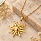 Gold sunburst charm pendant necklace with snake chain displayed on soft beige background