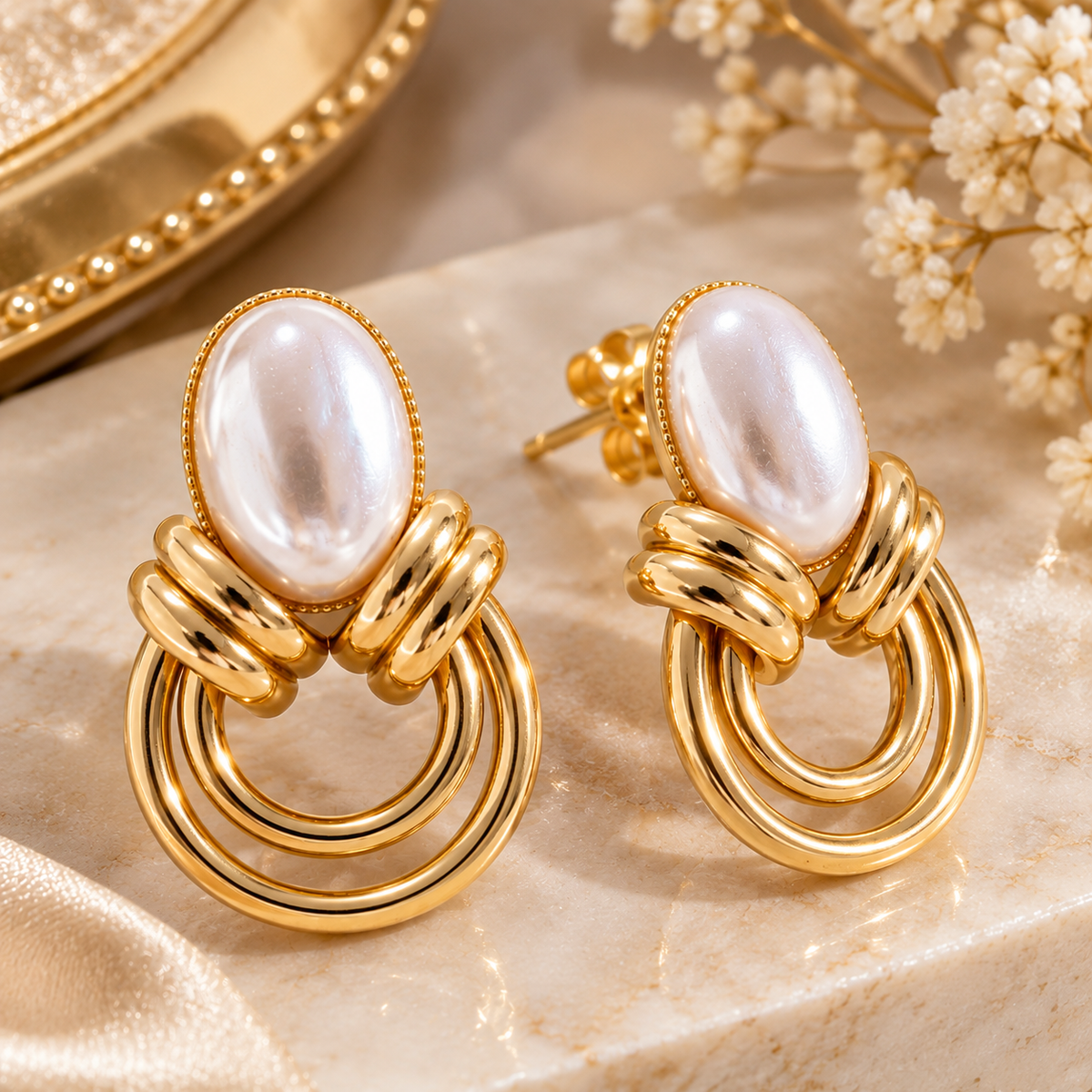 Close-up of gold-tone pearl drop earrings with a decorative background