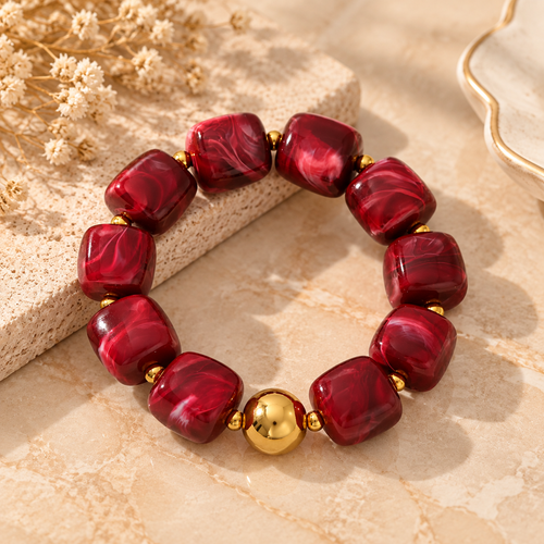 Red acrylic geometric bead bracelet displayed from angle view with stainless steel accents